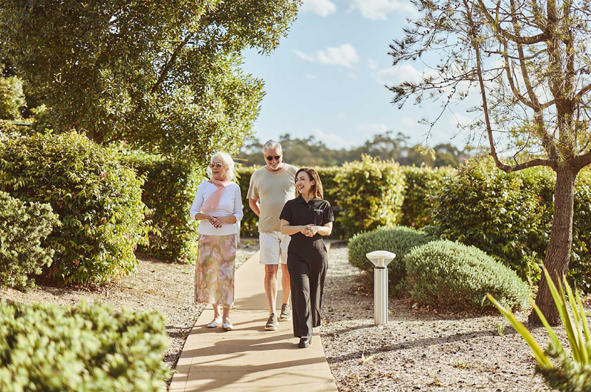 Retired couple walking around a retirement village with a Levande team member.