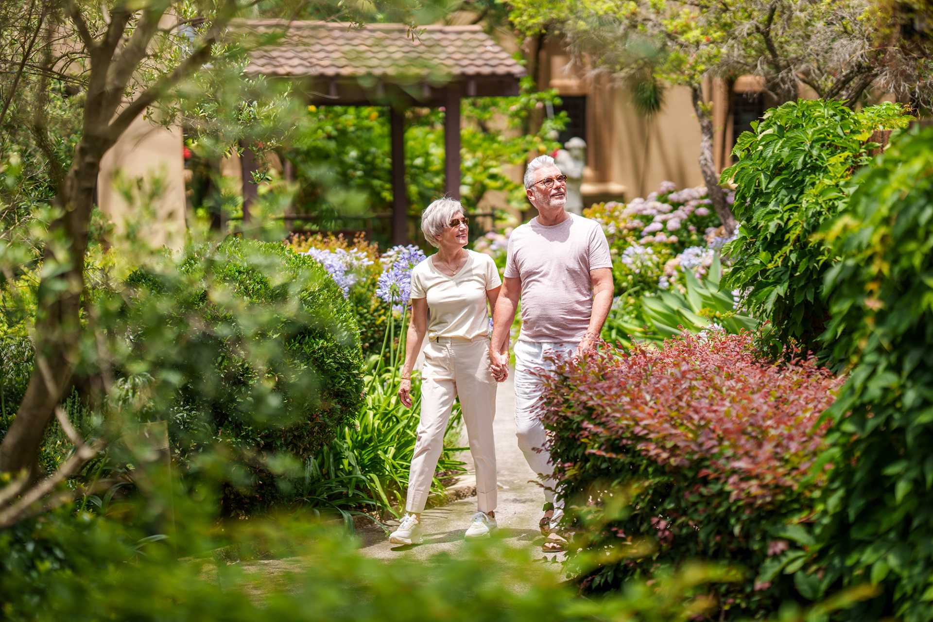 Retired couple walking around manicured gardens in a retirement village in Australia.